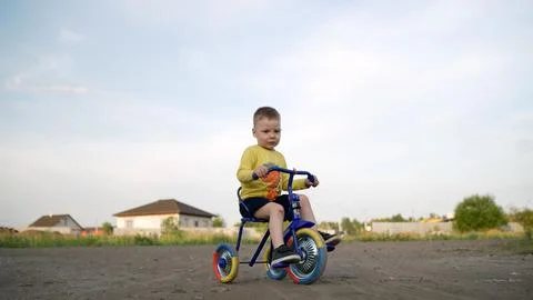 The kid explores nature on a bicycle. A child rides a tricycle in a new vil.. Stock Photos
