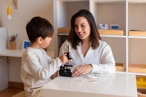 Kid exploring science with a microscope and mother or teacher help. Homeshool Stock Photos