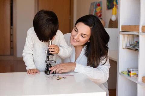 Kid exploring science with a microscope and mother or teacher help. Homeshool Stock Photos
