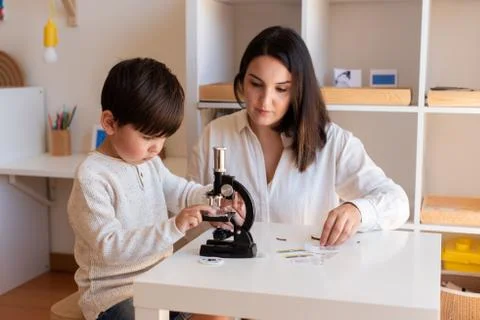 Kid exploring science with a microscope and mother or teacher help. Homeshool Stock Photos