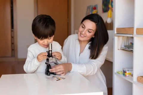 Kid exploring science with a microscope and mother or teacher help. Homeshool Stock Photos