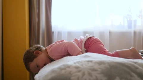 The kid is exploring the world, lying on the bed and looking down. 1920x1080 Stock Footage 147139083