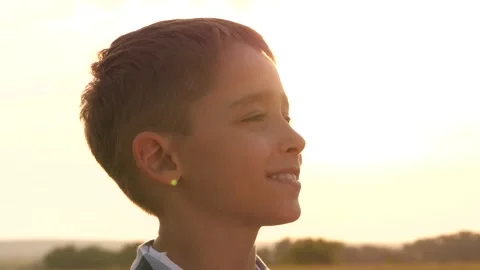 The kid face in close-up. A happy dream boy in sunset, his face is in the rays Stock Footage 250252894