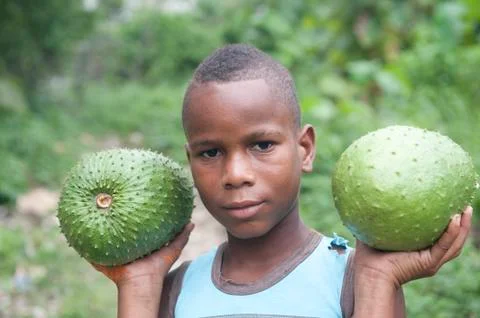 Kid facing the camera with two tropical fruits on their hands capurgana colombia Stock Photos