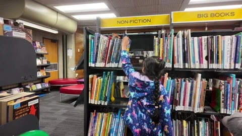 A kid finding a non-fiction book in library Stock Footage 327614448