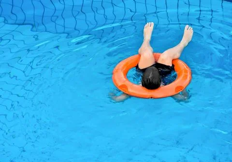 Kid on float upside down in pool Stock Photos