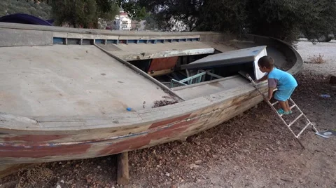 Kid gets onboard of old dry boat Stock Footage