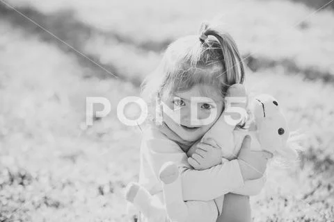 Kid girl hug soft horse toy on sunny day Stock Photos