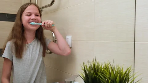 Kid girl laughing while brushing her teeth in bathroom at home Stock Footage 264848442