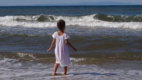Kid girl play walk in shallow sea waterline enjoy happy leisure rushing waves Stock Footage