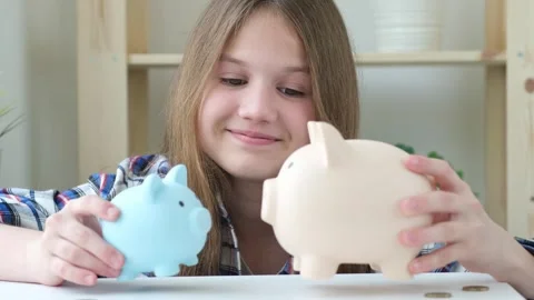 Kid girl playing with two piggy banks. Financial education for children Stock Footage 287237853