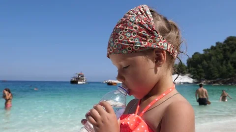Kid girl portrait drink bottle clear pure water on summer beach Greece leisure Stock Footage