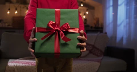 Kid gives gift box to camera. Unrecognizable kid hands presenting surprise box Stock Footage 285560229