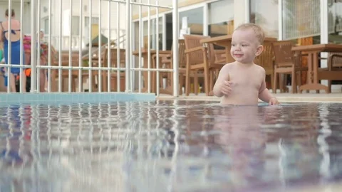 The Kid goes around the children's pool on the street. He enjoys water and plays Stock Footage 76475269