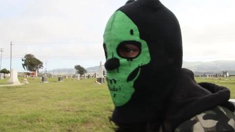Kid in graveyard puts on skeleton mask Stock Footage 155385360
