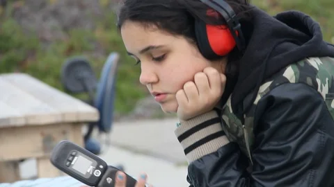 Kid on gun range on her phone looking bored Stock Footage 113912183