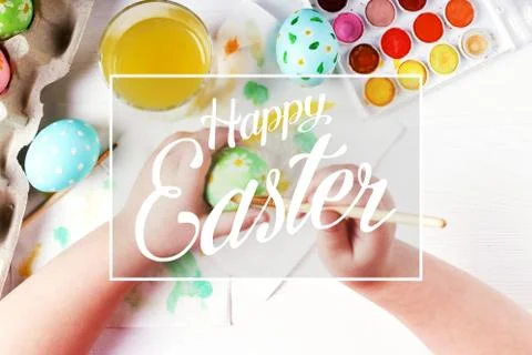 Kid hand painted boiled Easter eggs, paints and brushes on a white table. Pre Stock Photos