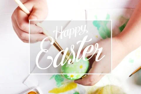 Kid hand painted boiled Easter eggs, paints and brushes on a white table. Pre Stock Photos