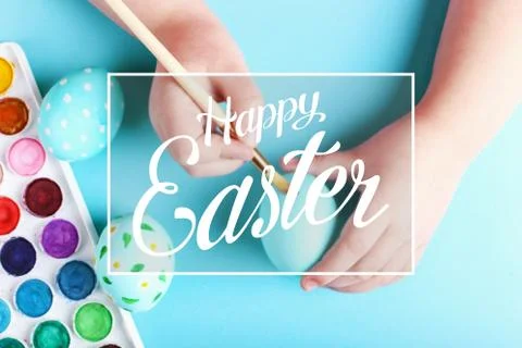 Kid hand painted boiled Easter eggs, paints and brushes on a blue background. Stock Photos
