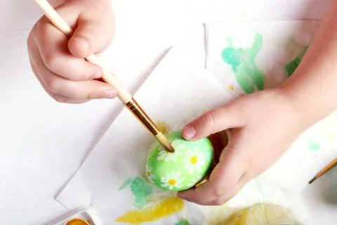 Kid hand painted Easter eggs, paints and brushes on a white table. Preparatio Stock Photos