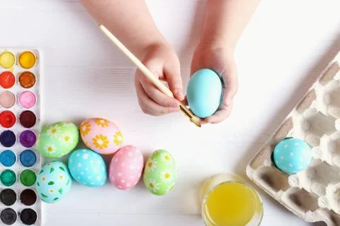 Kid hand painted Easter eggs, paints and brushes on a white table. Preparatio Stock Photos