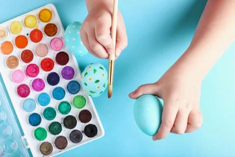Kid hand painted Easter eggs, paints and brushes on a blue background. Prepar Stock Photos