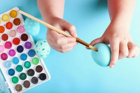 Kid hand painted Easter eggs, paints and brushes on a blue background. Prepar Stock Photos