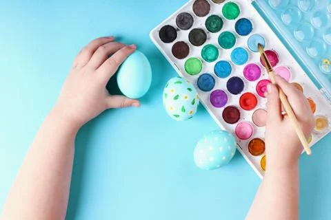 Kid hand painted Easter eggs, paints and brushes on a blue background. Prepar Stock Photos