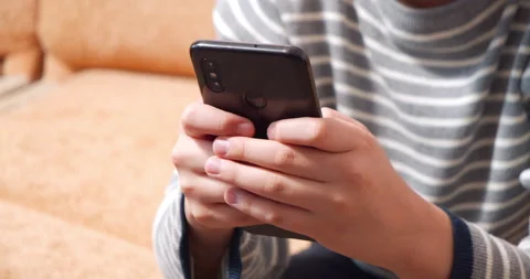 Kid hands holding smartphone while playing video game or typing message Stock Footage 146730989