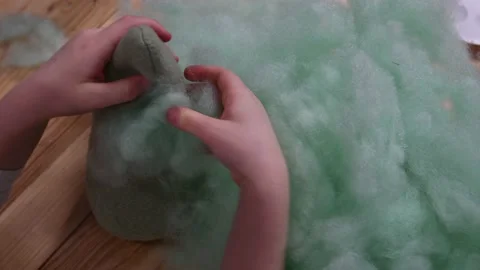 Kid hands make stuffed toy using sintepon hollow cotton filling Video stock 154001603