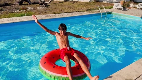 Kid have fun in a swimming pool jump backwards on rubber ring Stock Footage 269913404