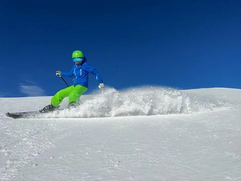Kid have ski fun launch a flurry of snow into the air on slope Stock Photos
