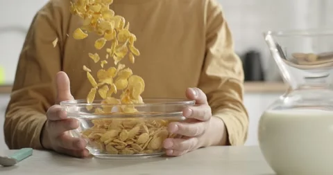 Kid having cereal corn flakes for breakfast. Close-up corn flakes falling into Stock Footage 267610201