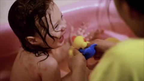 The kid is having fun bathing in a small pink bathtub Stock Footage 147669358