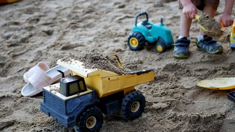 Kid having fun playing in sand. Child filling his toy dump truck with shovel Stock Footage 122283417