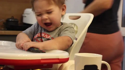 Kid is having fun sitting in his chair in the kitchen at home Video stock 123066011