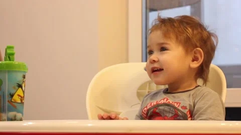 Kid is having fun sitting in his chair in the kitchen at home Stock Footage 123066038