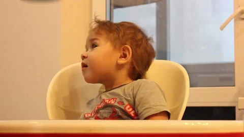 Kid is having fun sitting in his chair in the kitchen at home Video stock 123066057
