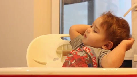 Kid is having fun sitting in his chair in the kitchen at home Video stock 123066061