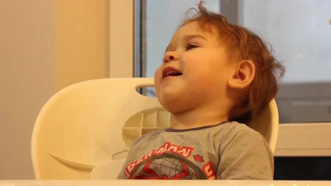 Kid is having fun sitting in his chair in the kitchen at home Video stock 123066066