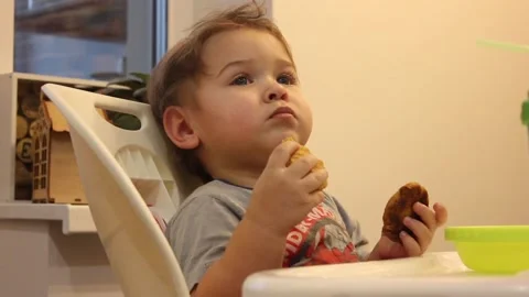 Kid is having fun sitting in his chair in the kitchen at home Video stock 123066107