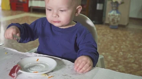 The kid is having lunch at the restaurant. In the hands of a spoon and fork Stock Footage 84789683