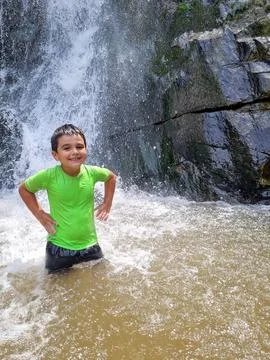 Kid having a refreshing waterfall bath Stock Photos