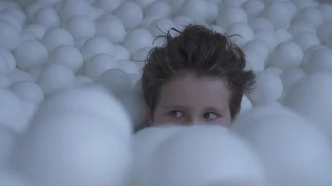 Kid hiding in a pool with balls Stock Footage 91906355