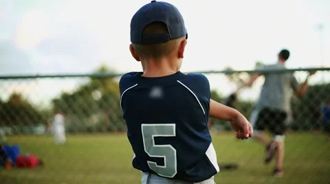 Kid on his baseball uniform stretching behind fence before baseball practice Stock Footage 47712892