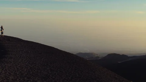 Kid on his father shoulders walking on the edge of Mount Etna Stock Footage 88565598