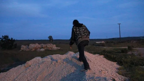 Kid holding gun walking around on dirt hill Stock Footage 114262032