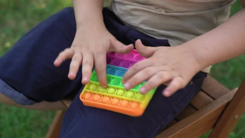 Kid Holding Rainbow Pop It Fidget Toy in Hands. Stock Footage 158982255