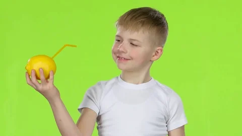 Kid holds a lemon through a straw drinking lemon juice, and shows a thumbs up Stock Footage 75786509