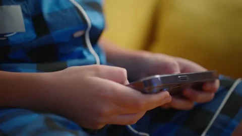 Kid interacts with smartphone while sitting on a couch in a cozy room Stock Footage 303799731